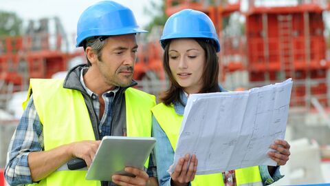 Der Landesbetrieb Bau und Immobilien Hessen (LBIH) vergibt Planungs- und Beratungsleistungen in allen Ingenieurdisziplinen und in allen Leistungsphasen mit Ausnahme der nicht delegierbaren Bauherrenaufgaben an Freischaffende. Eine Architektin und ein Architekt stehen auf einer Baustelle und schauen sich einen Bauplan an.