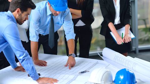 Architektinnen und Architekten arbeiten an einem Bauplan.