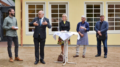 Fünf Personen stehen vor einem Gebäude