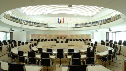 Statt der frontalen Sitzordnung im alten Plenarsaal ist die Bestuhlung des neuen Plenarsaals kreisförmig konzipiert mit dem Ziel, die Kommunikation zu fördern. Im Bild ist der Plenarsaal des Hessischen Landtages zu sehen. Die Bestuhlung des Plenarsaals ist kreisförmig konzipiert, helle Ahornholzmöbel verleihen dem Raum eine helle, freundliche Atmosphäre.