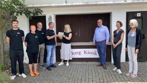 Bildunterzeile: Das Team von Christoph Herrmann (4. von links) hat den Kiosk auf Burg Frankenstein angemietet. LBIH-Niederlassungsleiterin Sabina Freienstein überreichte den Mietvertrag; dabei waren Bürgermeister Niels Starke sowie Susanne Ritter und Karin Tzschoppe (LBIH)